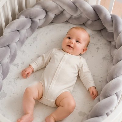 Tresse de lit gris bébé joyeux dans son berceau